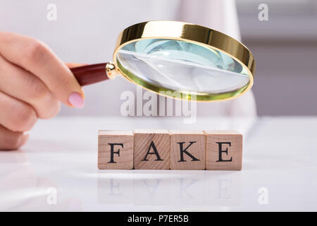 Close-up di una imprenditrice la mano di esaminare i blocchi di legno che mostra Fake parola Foto Stock