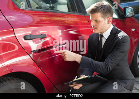 Agente di Assicurazione Assicurazione di riempimento forma vicino danneggiato auto rossa Foto Stock