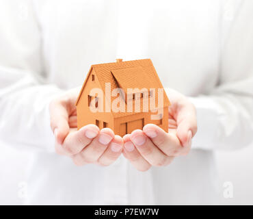 Piccola casa arancione in mani Foto Stock