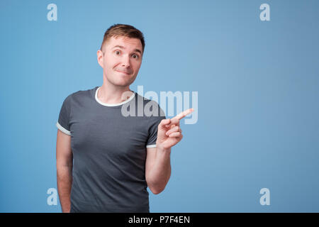 Unione di mezza età uomo promotore presentando mentre puntando al lato isolato su uno sfondo blu Foto Stock