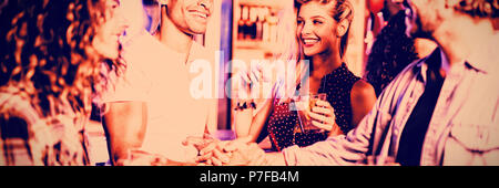 Amici facendo handshake dal contatore in club Foto Stock