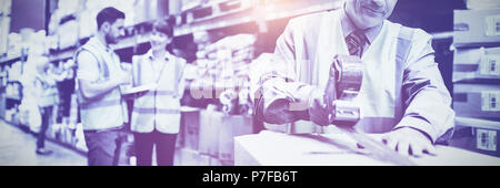 Lavoratore di magazzino la sigillatura di scatole di cartone per la spedizione Foto Stock