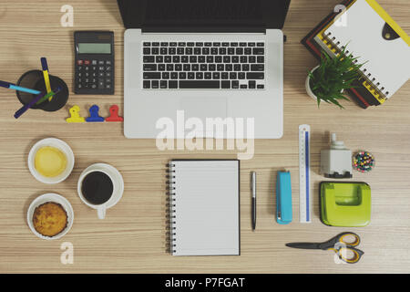 Più articoli di cancelleria per ufficio e per la scuola e un computer portatile. Forniture per uffici su uno sfondo di legno. Foto Stock