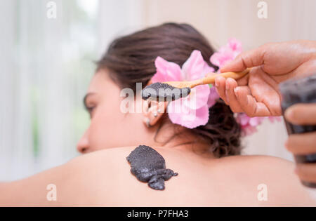 Applicazione a mano di nero carbone spa scrub sulle donne indietro Foto Stock