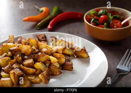 Le patatine fritte con piccoli pezzi di carne di maiale grassa carne, cipolla e aglio su piastra Foto Stock