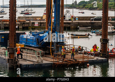 Schull, West Cork, Irlanda. 6 Luglio, 2018. Lavoratori edili e ingegneri di controllare la posizione della costruzione chiatta per facilitare l'installazione di pali che supporterà il nuovo pontile in Schull Harbour. Il lavoro è prevista per le 4 settimane e costano circa € 500.000. Credito: Andy Gibson/Alamy Live News. Foto Stock