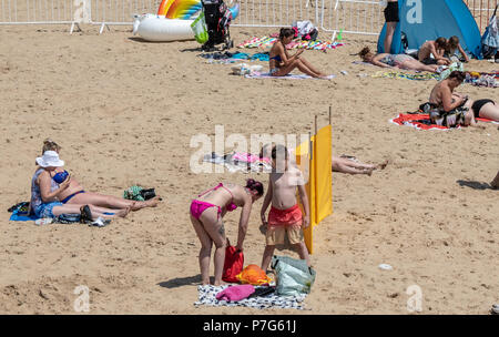 Bournemouth, Regno Unito. 6 luglio 2018. Le persone che usano i loro telefoni cellulari mentre sulla spiaggia di Bournemouth durante la canicola di luglio. Credito: Thomas Faull / Alamy Live News Foto Stock