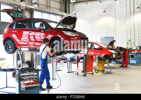 La sostituzione di un pneumatico sulla vettura da meccanica in un workshop Foto Stock