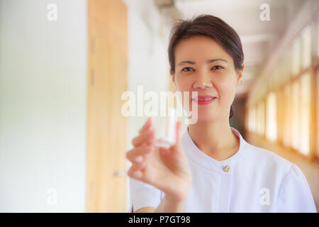 Donna sorridente infermiere azienda pillola coppa in mano per i pazienti. Professional, Specialista, infermiere, Dottore in bianco uniforme del concetto. Foto Stock