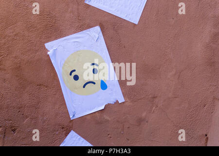 Il pianto carattere emoji stampato su carta e bloccati su una parete Foto Stock