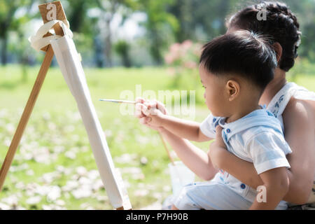 Asian little boy e sorella e disegnare insieme nel parco. I ragazzi di pittura e disegno. I bambini dipingere con il pennello di colore e matite. Arte e Mestieri per tod Foto Stock