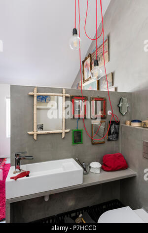 Una selezione di piccoli specchi vintage in bagno di appartamento loft con rosso cavo illuminazione Foto Stock