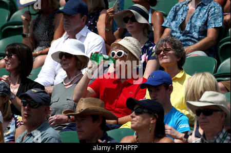 Spettatori proteggersi dal sole sulla corte 2 il giorno cinque dei campionati di Wimbledon al All England Lawn Tennis e Croquet Club, Wimbledon. Foto Stock