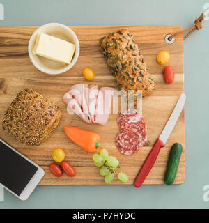 Ingredienti per preparare altri toast sulla tavola di legno con lo smartphone Foto Stock