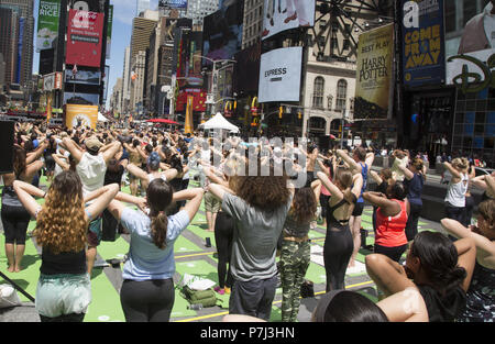 Gli appassionati di Yoga prendere lezioni gratuite nell'annuale Times Square solstizio d estate la celebrazione con le classi per tutta la giornata in mezzo al materiale sfarzo del quartiere di New York City. Foto Stock