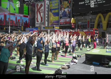 Gli appassionati di Yoga prendere lezioni gratuite nell'annuale Times Square solstizio d estate la celebrazione con le classi per tutta la giornata in mezzo al materiale sfarzo del quartiere di New York City. Foto Stock