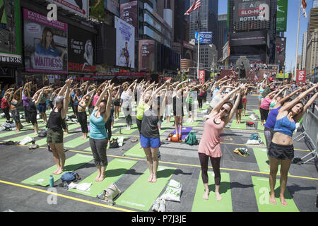 Gli appassionati di Yoga prendere lezioni gratuite nell'annuale Times Square solstizio d estate la celebrazione con le classi per tutta la giornata in mezzo al materiale sfarzo del quartiere di New York City. Foto Stock