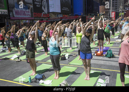 Gli appassionati di Yoga prendere lezioni gratuite nell'annuale Times Square solstizio d estate la celebrazione con le classi per tutta la giornata in mezzo al materiale sfarzo del quartiere di New York City. Foto Stock