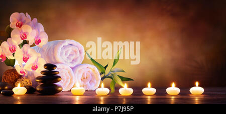 Concetto di Spa - Massaggio pietre con asciugamani e candele in fondo naturale Foto Stock