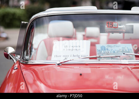 Una lettura del segno "Ciao, io parlo la lingua 6. Come posso aiutarla?" si siede nel parabrezza di un classico, rosso Chevy convertibile. Foto Stock