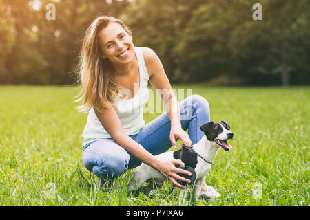 Bella donna la pettinatura il suo cane Jack Russell Terrier nella natura.Immagine è intenzionalmente tonica. Foto Stock