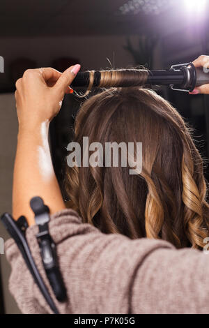 Parrucchiere rendendo un arricciamento dei capelli di un cliente Foto Stock