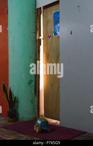 Una macchina giocattolo è nella parte anteriore di un do da dove si vede la luce all'interno. Il marcio pareti sono dipinte in arancione, verde e grigio e c'è un santo Geo Foto Stock