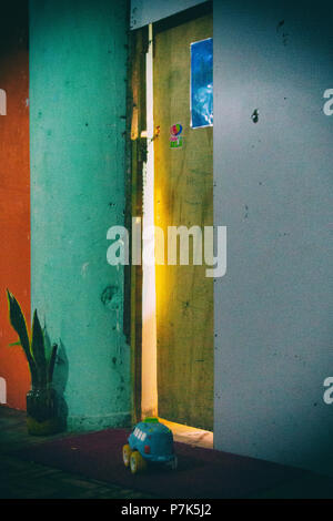 Una macchina giocattolo è nella parte anteriore di un do da dove si vede la luce all'interno. Il marcio pareti sono dipinte in arancione, verde e grigio e c'è un santo Geo Foto Stock