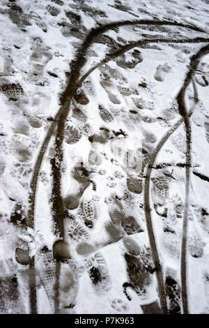 Calzatura stampe e pneumatico di una bicicletta di stampe sul sottile manto di neve di un marciapiede, Foto Stock