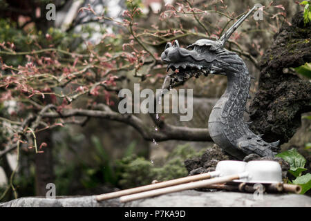 Una piccola fontana a forma di drago in un giardino giapponese Foto Stock