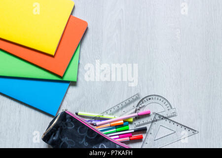 Colorate notebook bianco su sfondo di legno e matita caso con articoli di cartoleria Foto Stock