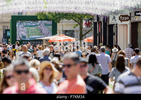 Bath, Regno Unito, 7 luglio, 2018. Come bagno gode di un altro molto calda e soleggiata giornata gli acquirenti sono ritratte godendo il sole in SouthGate shopping center dove un grande schermo è stato impostato in modo che gli appassionati di tennis possono guardare il torneo di Wimbledon Tennis Championship. Credito: lynchpics/Alamy Live News Foto Stock