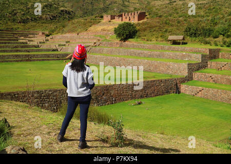 Un turista femminile guardando l'impressionante Inca Agricoltura e irrigazione rovine di Tipon nella Valle Sacra, regione di Cusco, Perù Foto Stock