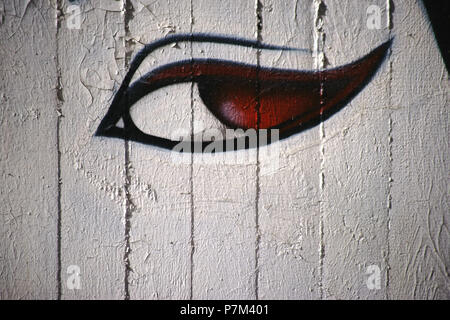 Una spruzzata o dipinte di donna con occhio rosso allievi su un muro di cemento. Foto Stock