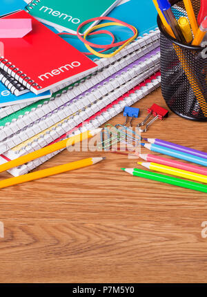 Pila di quaderni scolastici e altri materiali su una superficie in legno con spazio di copia Foto Stock