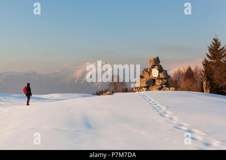 Un escursionista osserva la lapide partigiana sulla Costa Mount, Prealpi Bellunesi, Farra d'Alpago, provincia di Belluno, Veneto, Italia Foto Stock