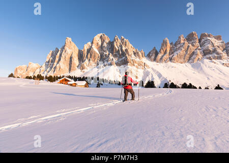 Un bellissimo tramonto in inverno sul Geisler in Villnössertal con un escursionista attonita di fronte a loro, Provincia Autonoma di Bolzano Alto Adige, Trentino Alto Adige, Italia Foto Stock