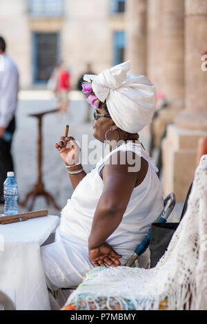 Teresa l'indovino di fumare un sigaro cubano e godersi il bel tempo in Plaza de la Catedral, Havana, Cuba. Foto Stock