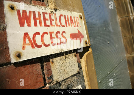 Accesso per la sedia a rotelle segno su edificio in disuso. Foto Stock