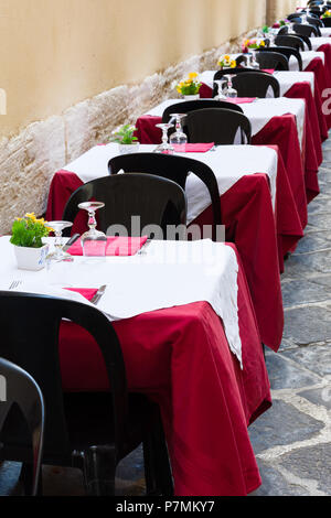 Set di tavoli e sedie vuote allineate in un ristorante in Ortigia, Siracusa, Italia Foto Stock