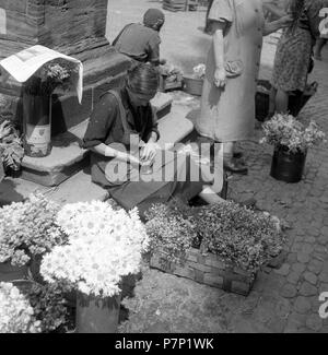 Venditore di fiori conta il suo reddito quotidiano, Freiburger Münstermarkt, circa Da 1945 a 1955, Freiburg, Germania Foto Stock