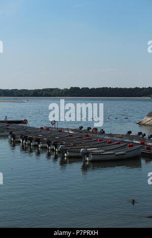 Waterfront scena - Ritratto di una linea di barche da pesca ormeggiate in acqua su un tardo pomeriggio al serbatoio Hanningfield, Essex, Gran Bretagna. Foto Stock