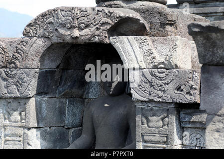 Borobudur, Indonesia - 23 Giugno 2018: un albero di luce attraversa il volto di una statua del Buddha al tempio buddista di Tempio di Borobudur, nei pressi di Jogjakarta Foto Stock