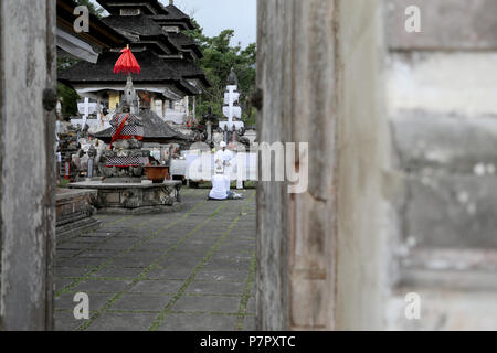 Amlapura, Indonesia - 5 Luglio 2018: un sacerdote tende ad un orante nel tempio di Lempuyang Luhur nella parte est di Bali, Indonesia Foto Stock