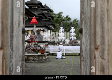 Amlapura, Indonesia - 5 Luglio 2018: un sacerdote tende ad un orante nel tempio di Lempuyang Luhur nella parte est di Bali, Indonesia Foto Stock