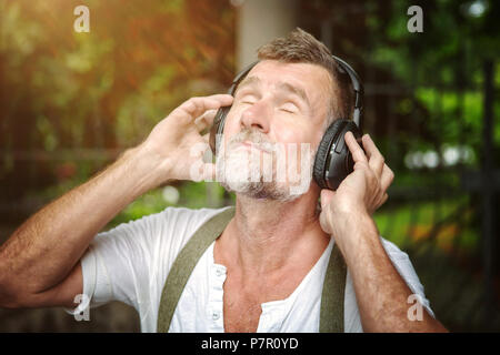 Ritratto di bello barbuto l uomo nella sua 50s con le cuffie Foto Stock