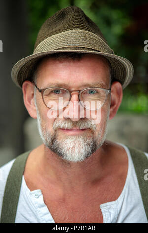 Ritratto di bello uomo barbuto con cappello e occhiali nella sua 50s Foto Stock