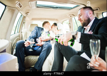 Groomsman aprire la bottiglia e versando champagni in bicchieri in auto. Foto Stock