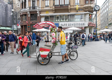 Un ombrello coperto per le biciclette taxi & il suo operatore in Stock Im Eisen platz in Vienna, Auastria. Foto Stock