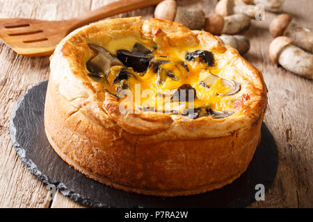 Torta casalinga, quiche con funghi selvatici, formaggio cheddar, pollo e crema di close-up sul tavolo orizzontale. Foto Stock